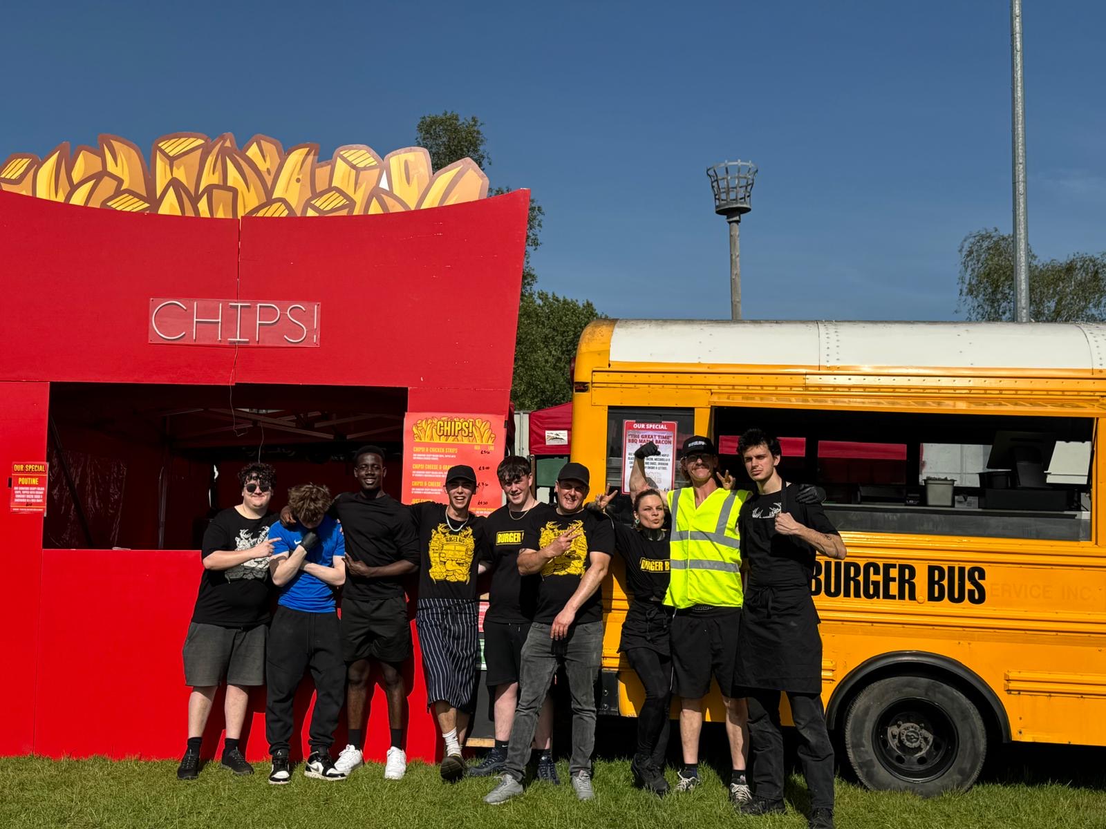 Burger Bus and Chips! crew posing between the giant chip box and the yellow bus